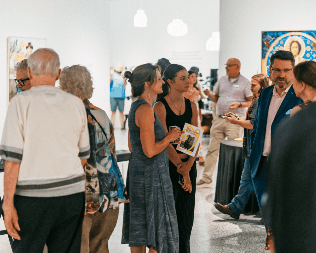 Small groups of people socialize in an art gallery setting