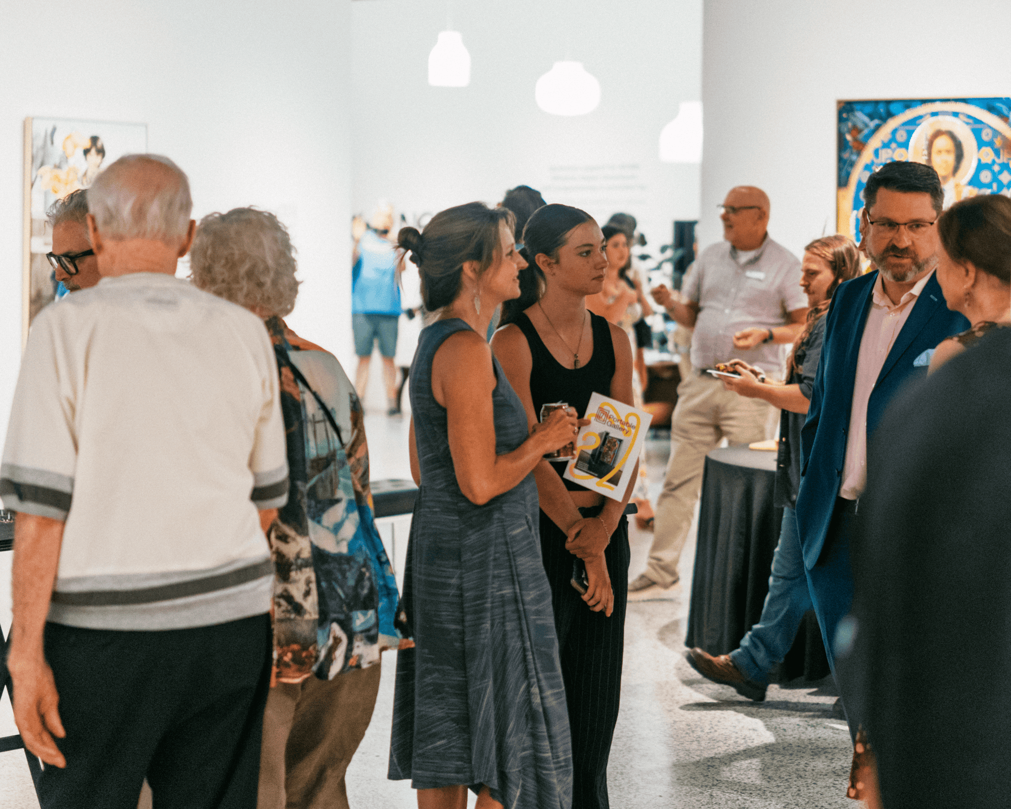 Small groups of people socialize in an art gallery setting